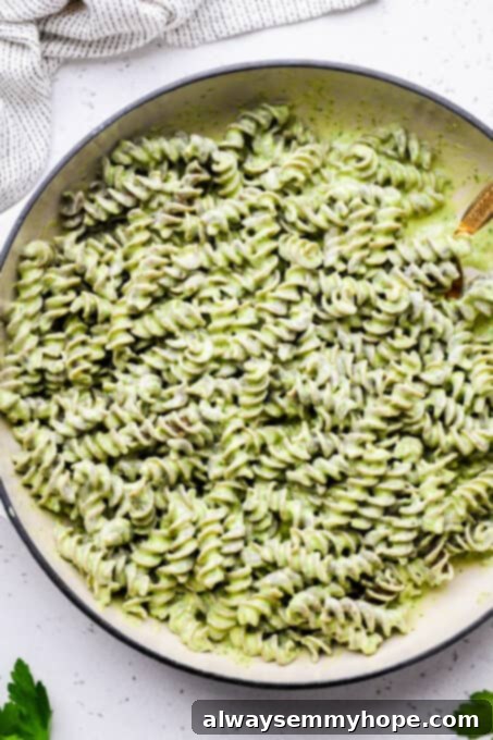 Divine Green Pasta 8 Creamy green goddess sauce perfectly coating lentil pasta in a pan, showcasing a vibrant, healthy, and delicious meal.