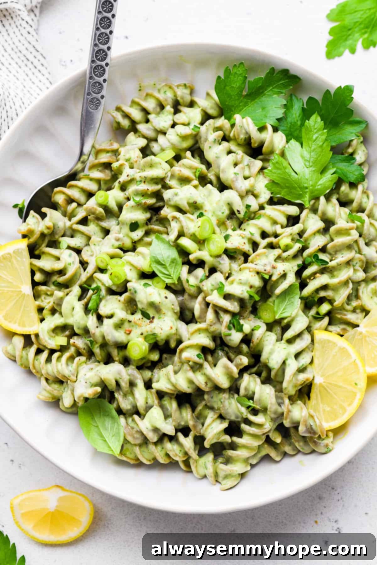 Divine Green Pasta 9 A delicious bowl of green goddess pasta garnished with a lemon wedge and fresh herbs, ready to be enjoyed as a wholesome meal.