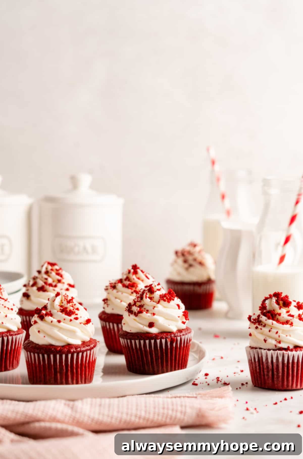 Decadent vegan red velvet cupcakes topped with luscious cream cheese frosting and a sprinkle of cake crumbs, elegantly arranged on a serving plate.