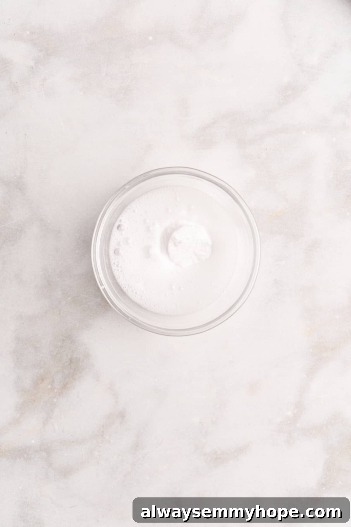 Overhead view of baking soda fizzing as it reacts with vinegar in a small bowl, showcasing the active leavening agents.