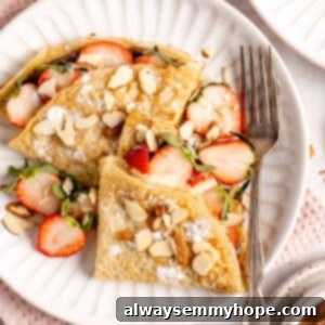 crepes on a plate with a fork with strawberries and almonds on top