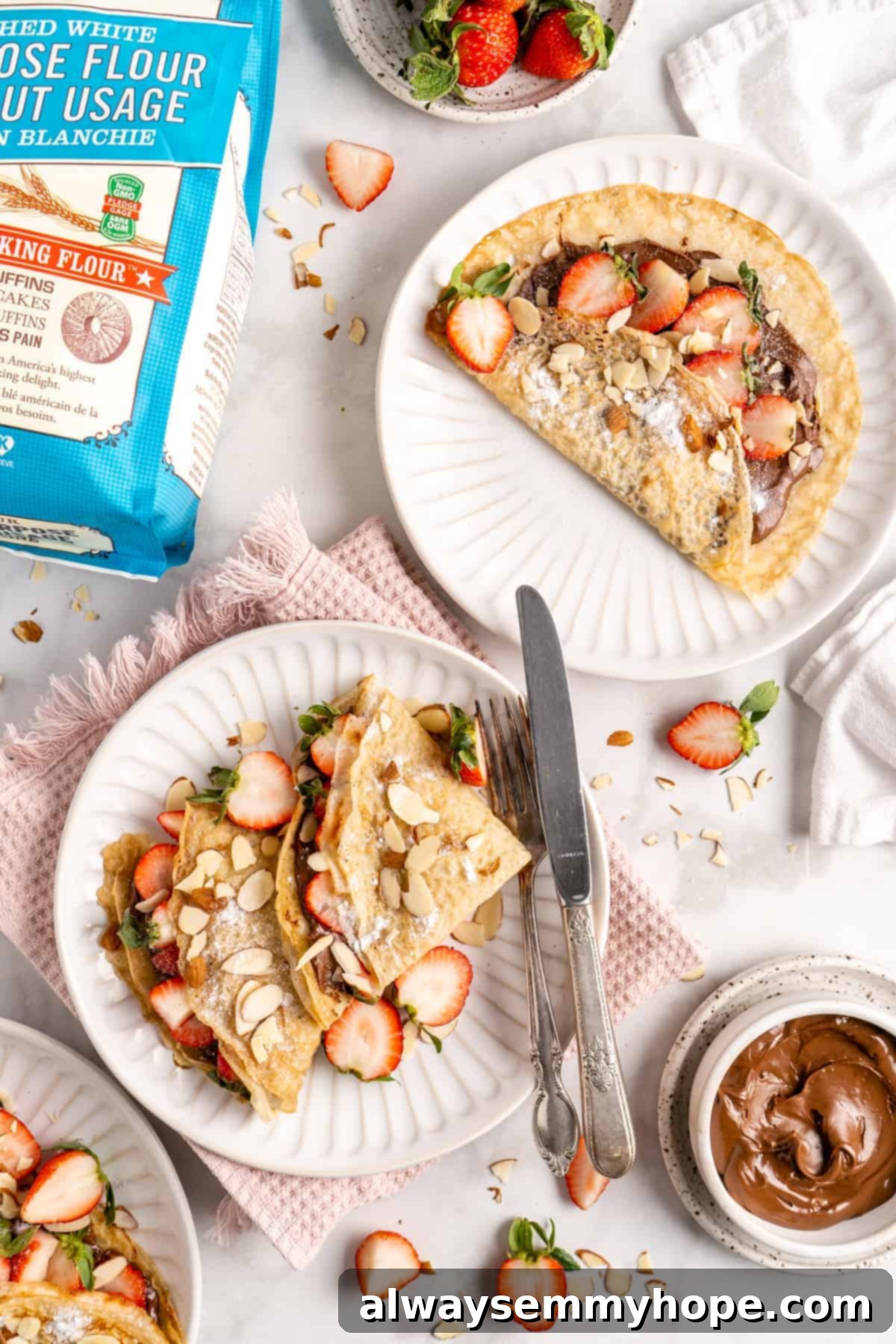 Overhead view of vegan crepes on plates with strawberries and hazelnut spread