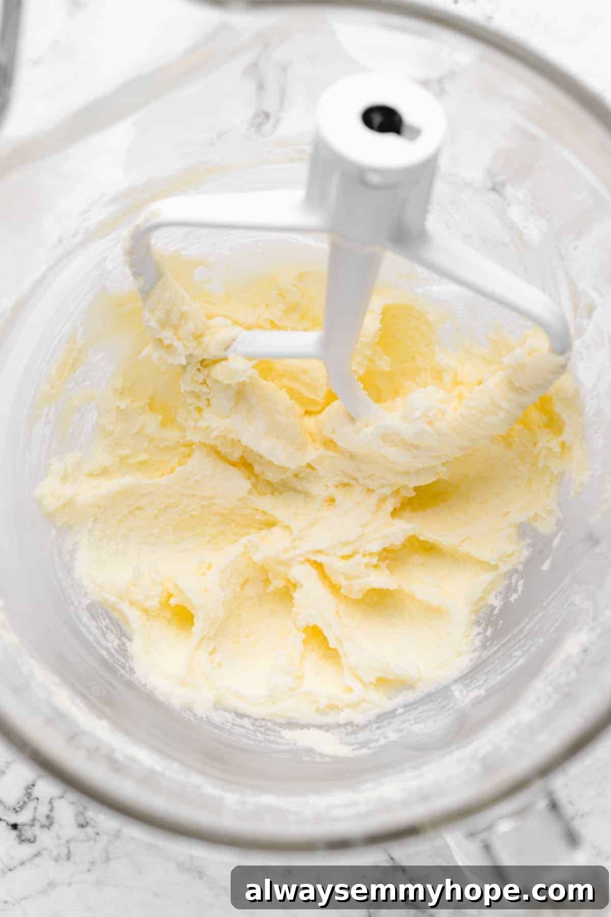 Butter and sugar being creamed in glass stand mixer bowl