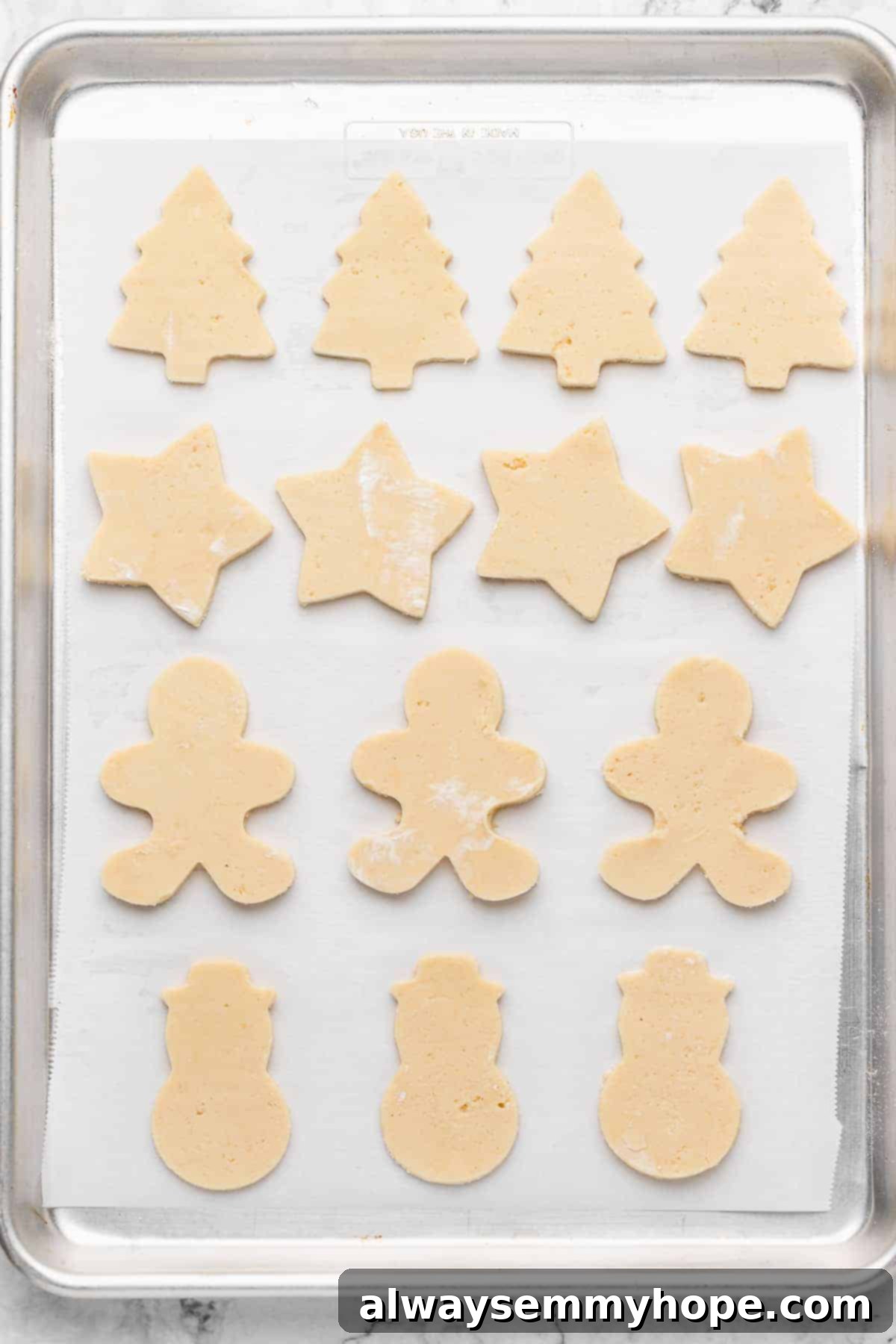 Overhead view of cut sugar cookie dough on parchment-lined baking sheet