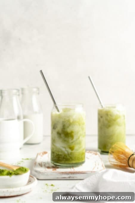 Smooth Iced Matcha Latte 13 Two beautifully prepared iced matcha lattes in glass tumblers with stainless steel straws, ready to be enjoyed.