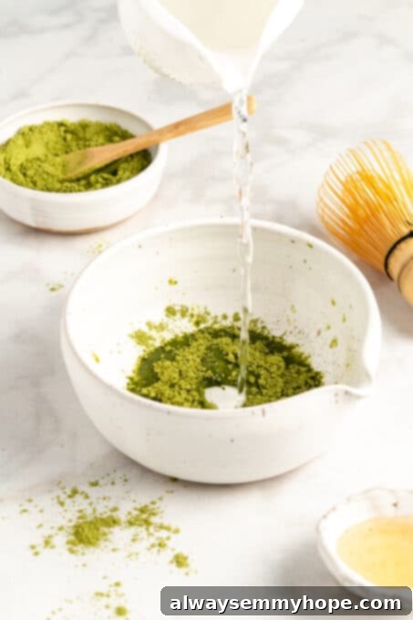 Smooth Iced Matcha Latte 7 Pouring hot water from a kettle into a bowl containing matcha powder, preparing for whisking.