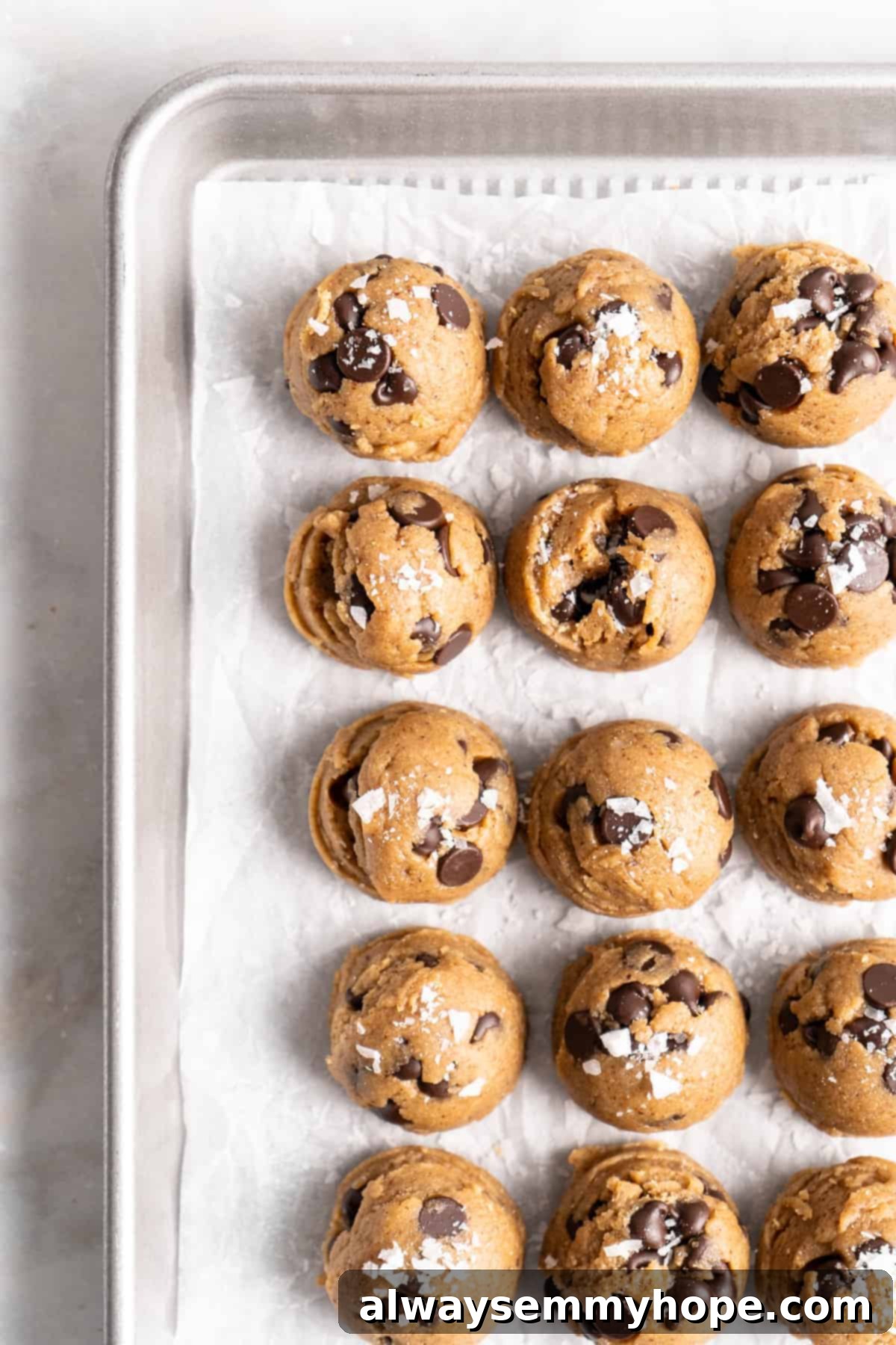 Overhead view of cookie dough balls arranged on parchment-lined baking sheet