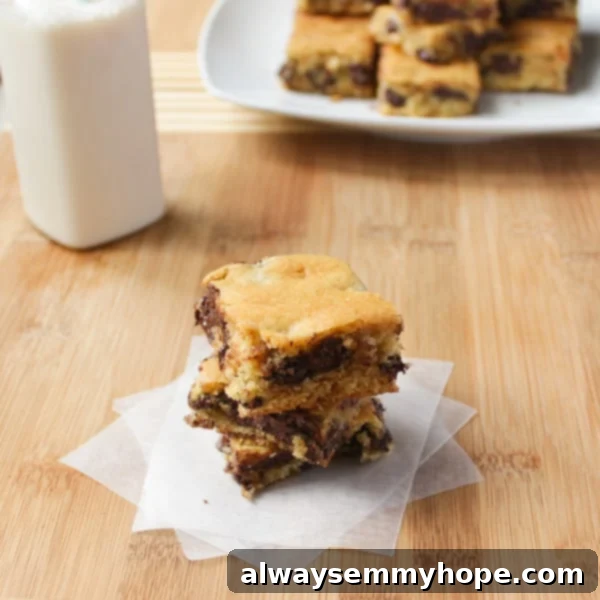 These Ghirardelli Chocolate Chip Cookie Bars were ah-mazing. Made with cream cheese and dark chocolate chips, they melt right in your mouth. Ghirardelli Chocolate Chip Cookie Bars on a wooden table.
