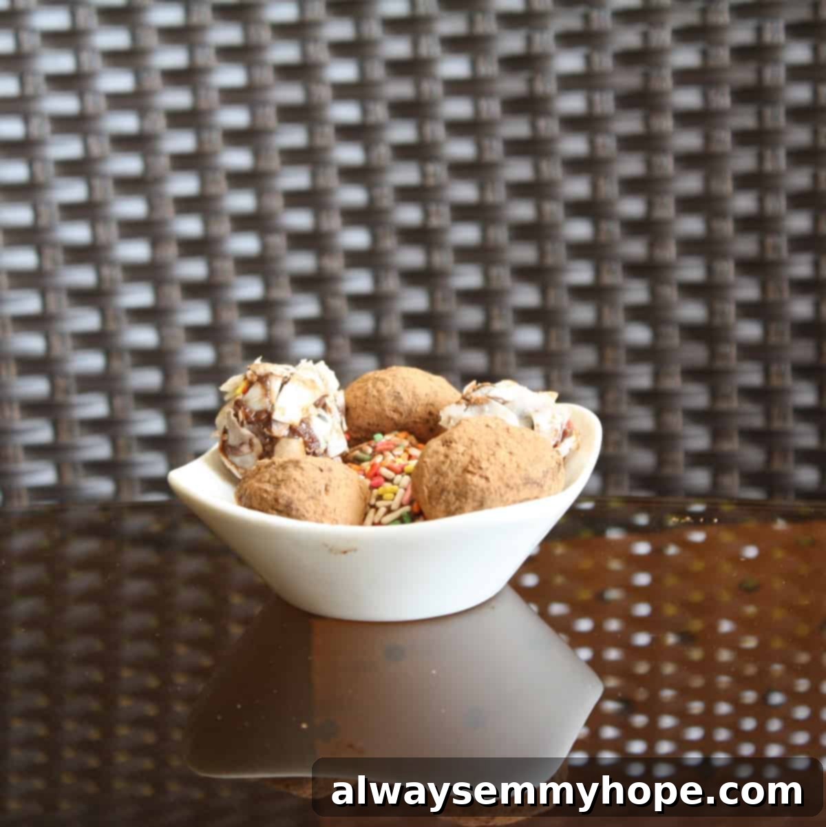 A beautifully arranged white bowl filled with classic rum balls, dusted with various toppings like cocoa powder, shredded coconut, and colorful sprinkles, ready to be enjoyed.