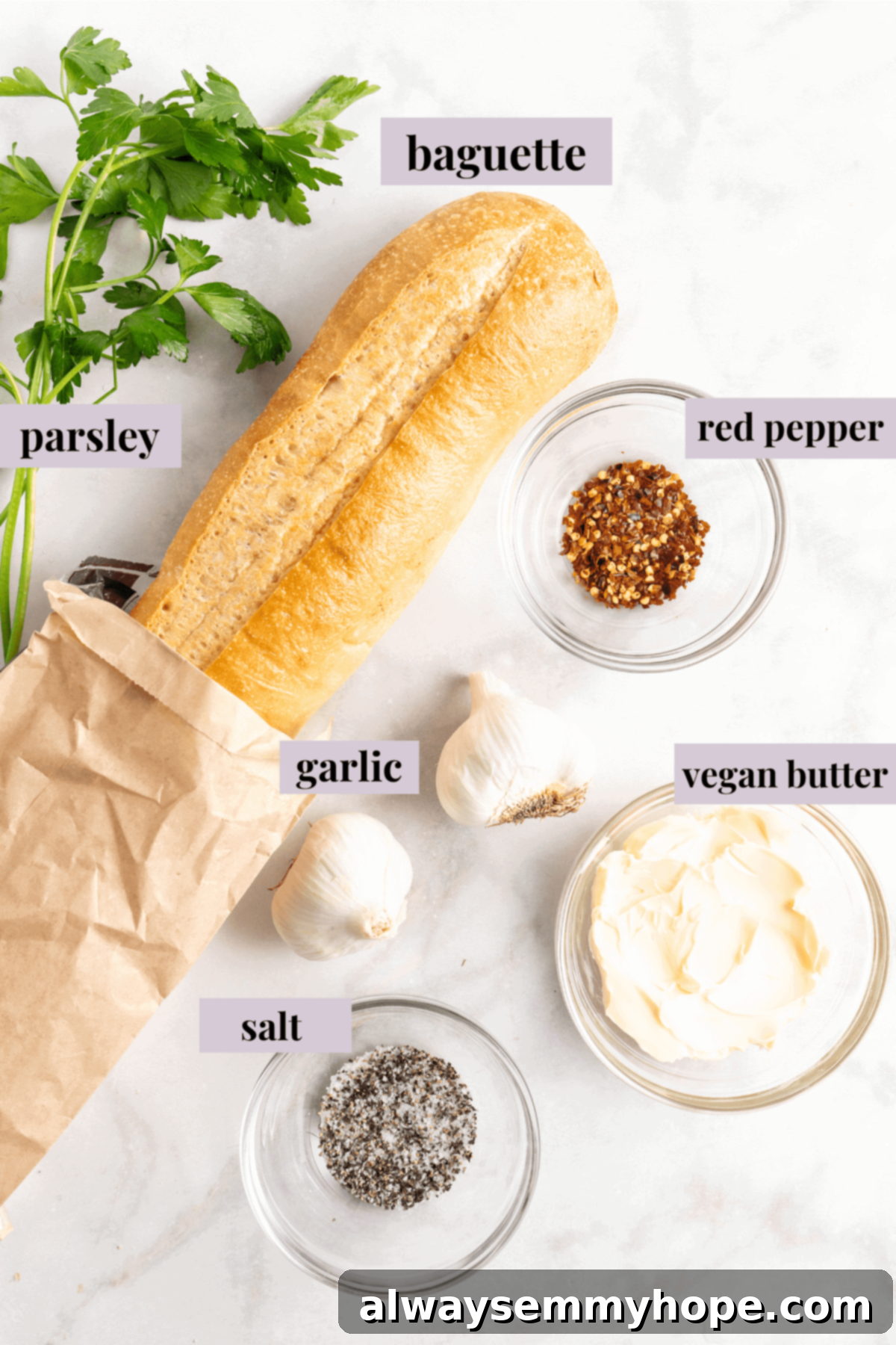 Overhead view of roasted garlic bread ingredients laid out on a table, including garlic heads, vegan butter, and herbs