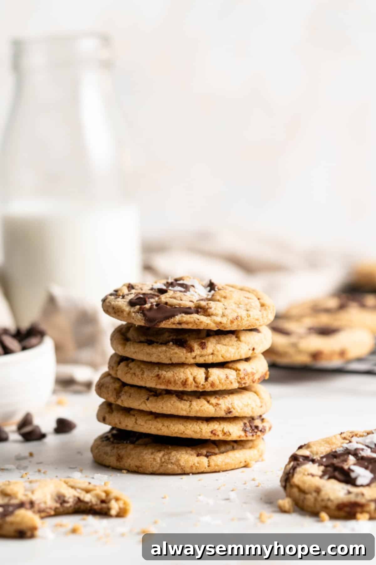 Plant-Based Chocolate Chip Bliss 14 A beautiful stack of soft and chewy vegan chocolate chip cookies, perfectly golden brown, with a pitcher of plant-based milk blurred in the background, creating an inviting scene for a delicious treat.