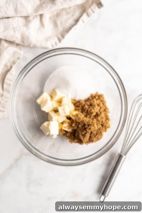 Plant-Based Chocolate Chip Bliss 4 Close-up overhead view of softened vegan butter, organic white sugar, and brown sugar measured into a clear glass mixing bowl, ready to be creamed for vegan chocolate chip cookies.