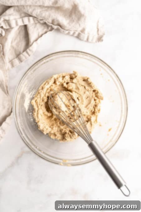 Plant-Based Chocolate Chip Bliss 5 Overhead view of creamed vegan butter, white sugar, brown sugar, vegan milk, and vanilla extract in a glass mixing bowl, ready for the dry ingredients to be added for plant-based chocolate chip cookies.
