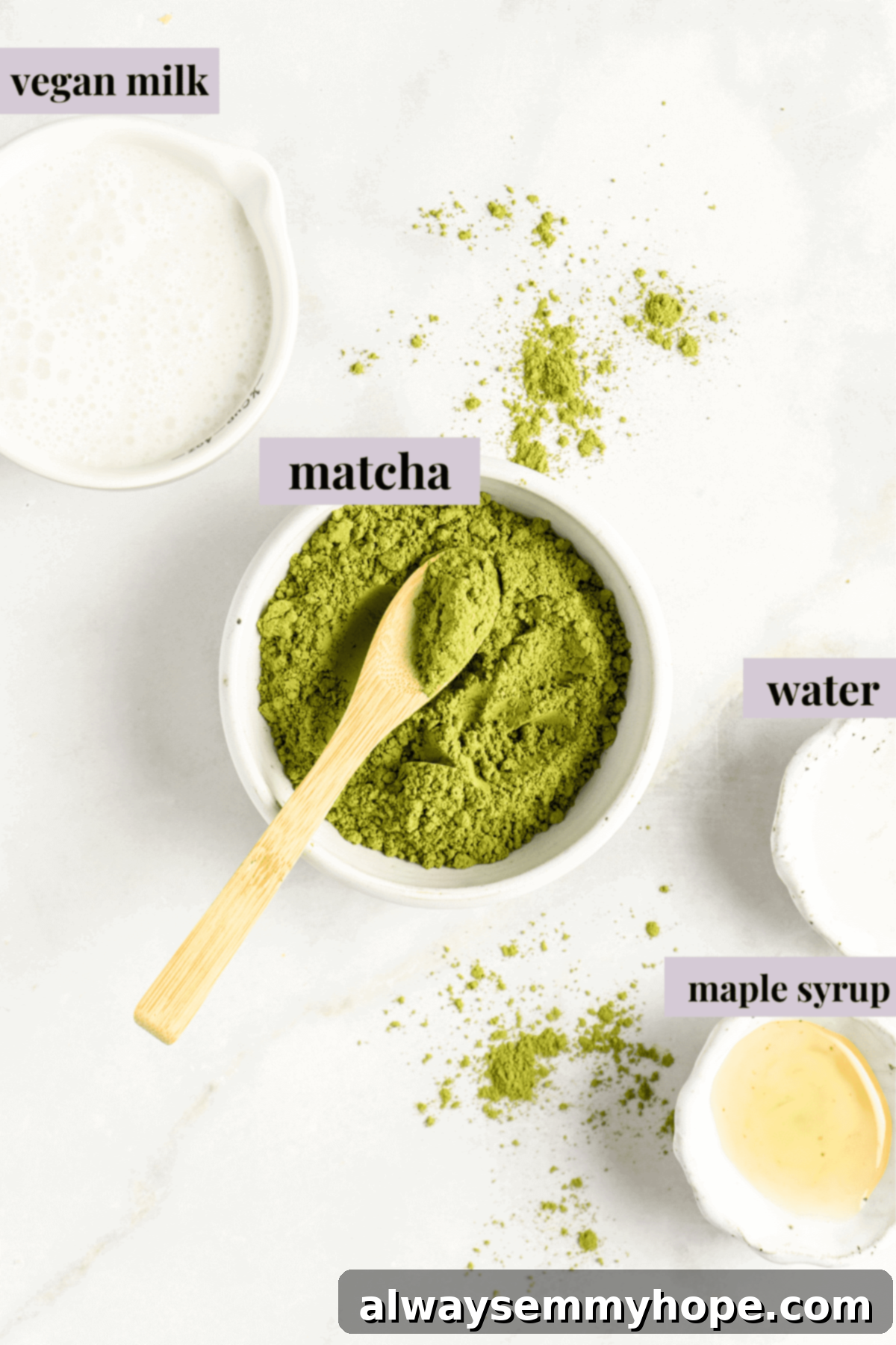 All the essential ingredients for making a delicious matcha latte laid out on a clean surface: matcha powder, hot water, sweetener, and plant-based milk.