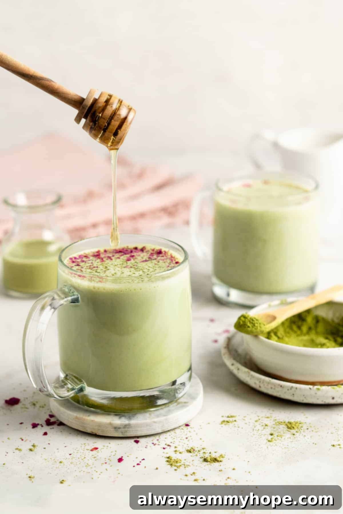 A delicate stream of agave nectar being drizzled into a glass mug of vibrant green matcha latte, adding a touch of sweetness.