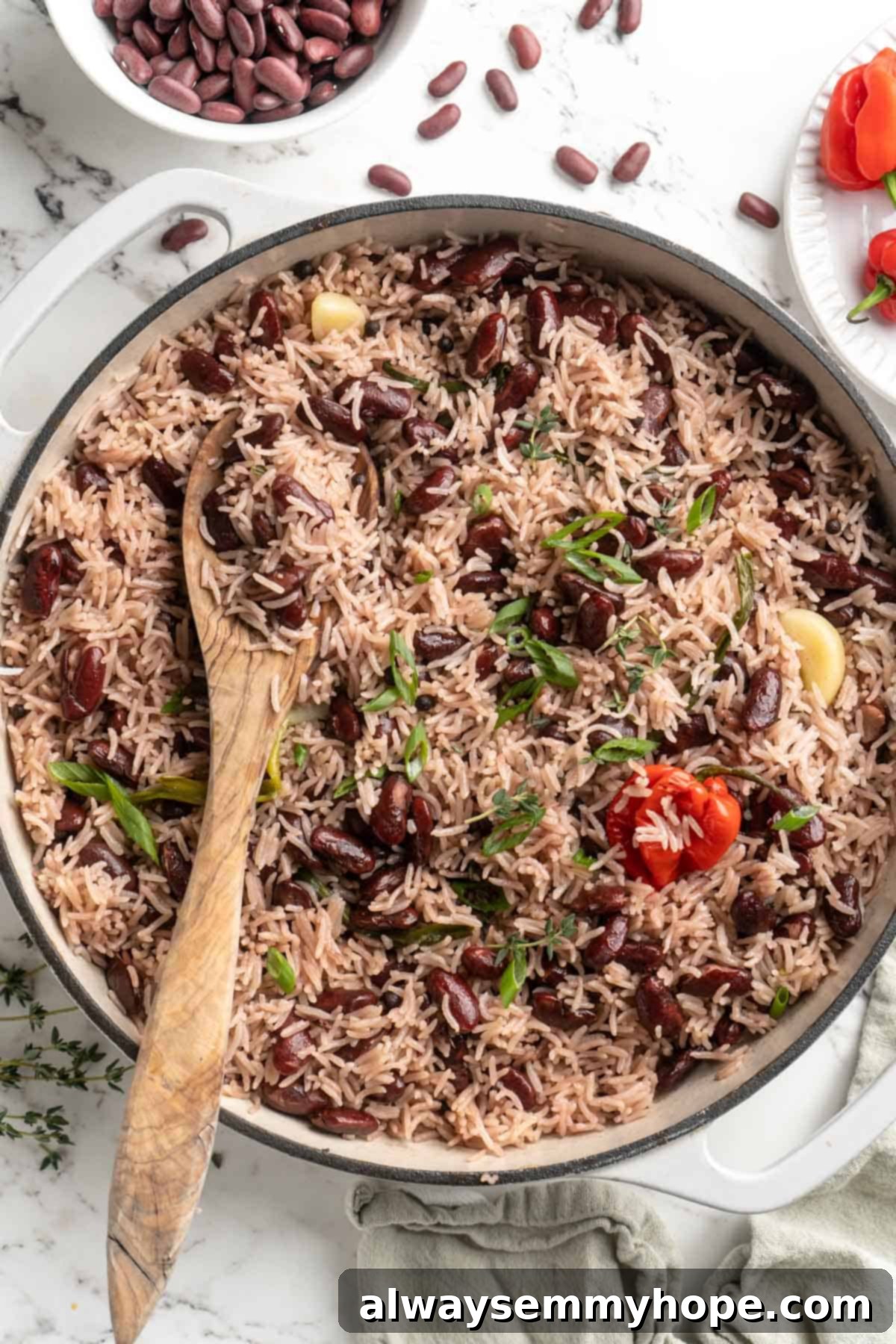 This authentic Jamaican rice and peas recipe is an easy side dish with lots of island vibes! It's packed with flavour and so simple to make. Overhead view of creamy Jamaican rice and peas in a vibrant blue pan, garnished with fresh thyme sprigs.