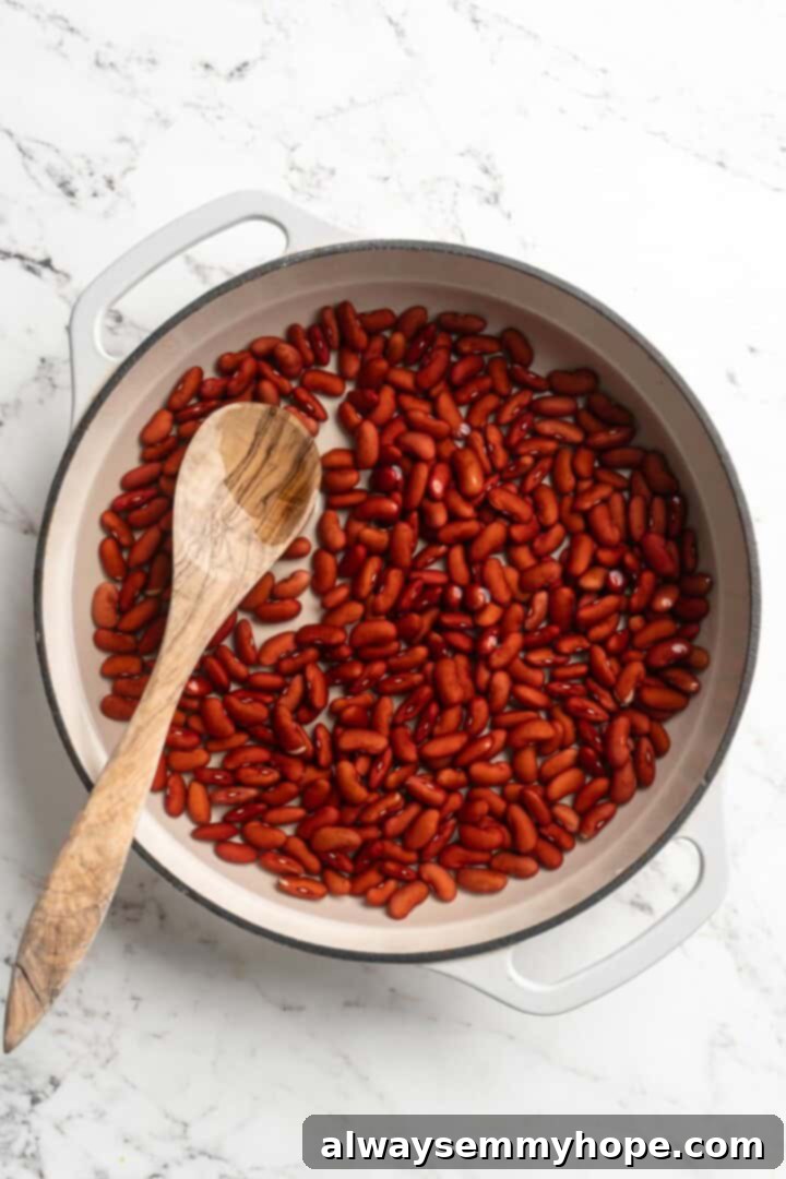 This authentic Jamaican rice and peas recipe is an easy side dish with lots of island vibes! It's packed with flavour and so simple to make. Dry kidney beans soaking in water in a pan, illustrating the first step of preparation.