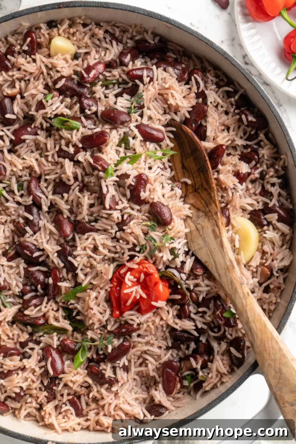 This authentic Jamaican rice and peas recipe is an easy side dish with lots of island vibes! It's packed with flavour and so simple to make. Top-down view of Jamaican rice and peas in a skillet, showcasing the inviting texture and vibrant color.