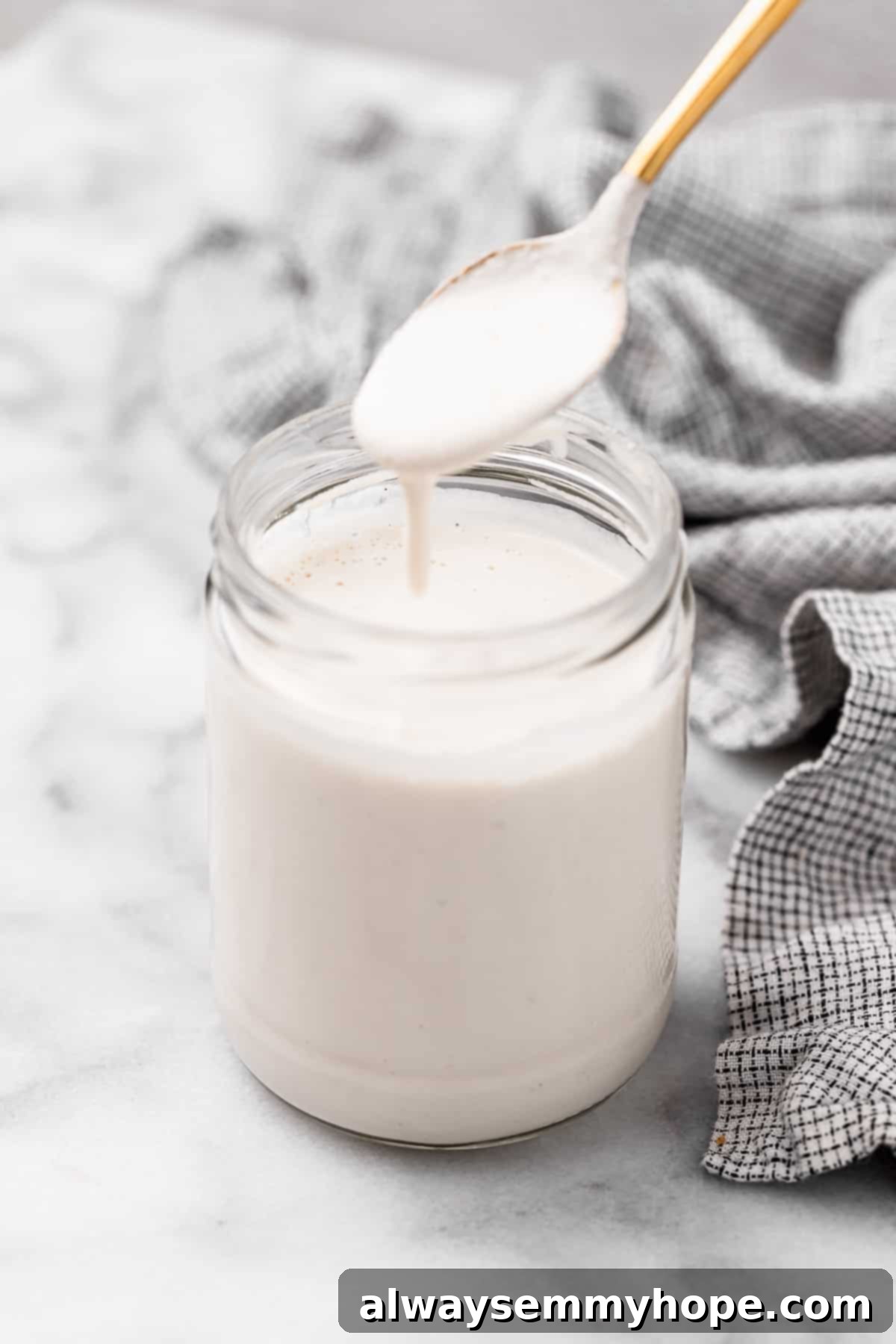 Spoonful of vegan heavy cream spilling into jar of cream