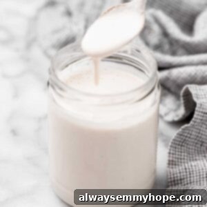 Spoonful of vegan heavy cream spilling into jar of cream