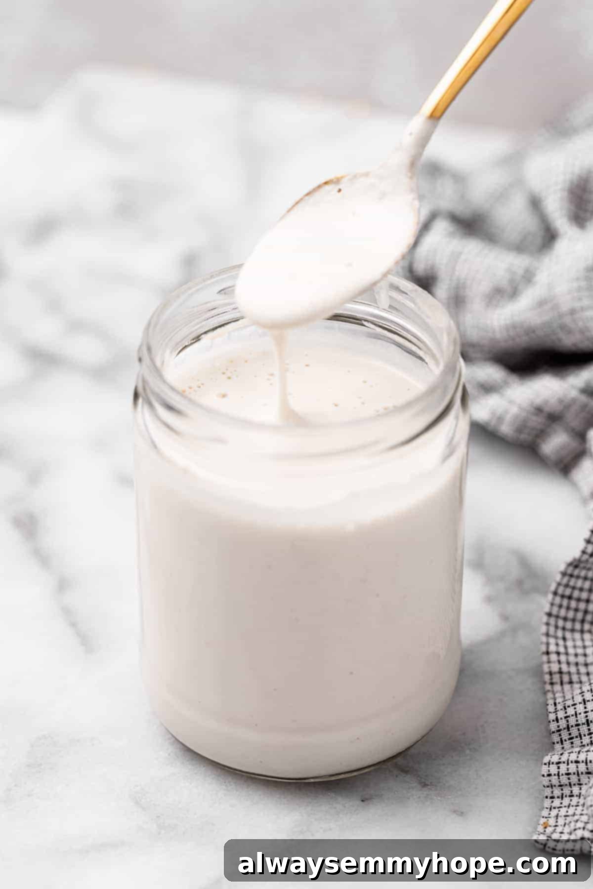 Spoonful of vegan heavy cream held over jar