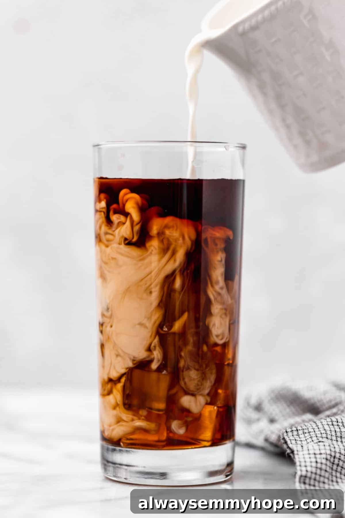 Vegan heavy cream being poured into glass of iced coffee
