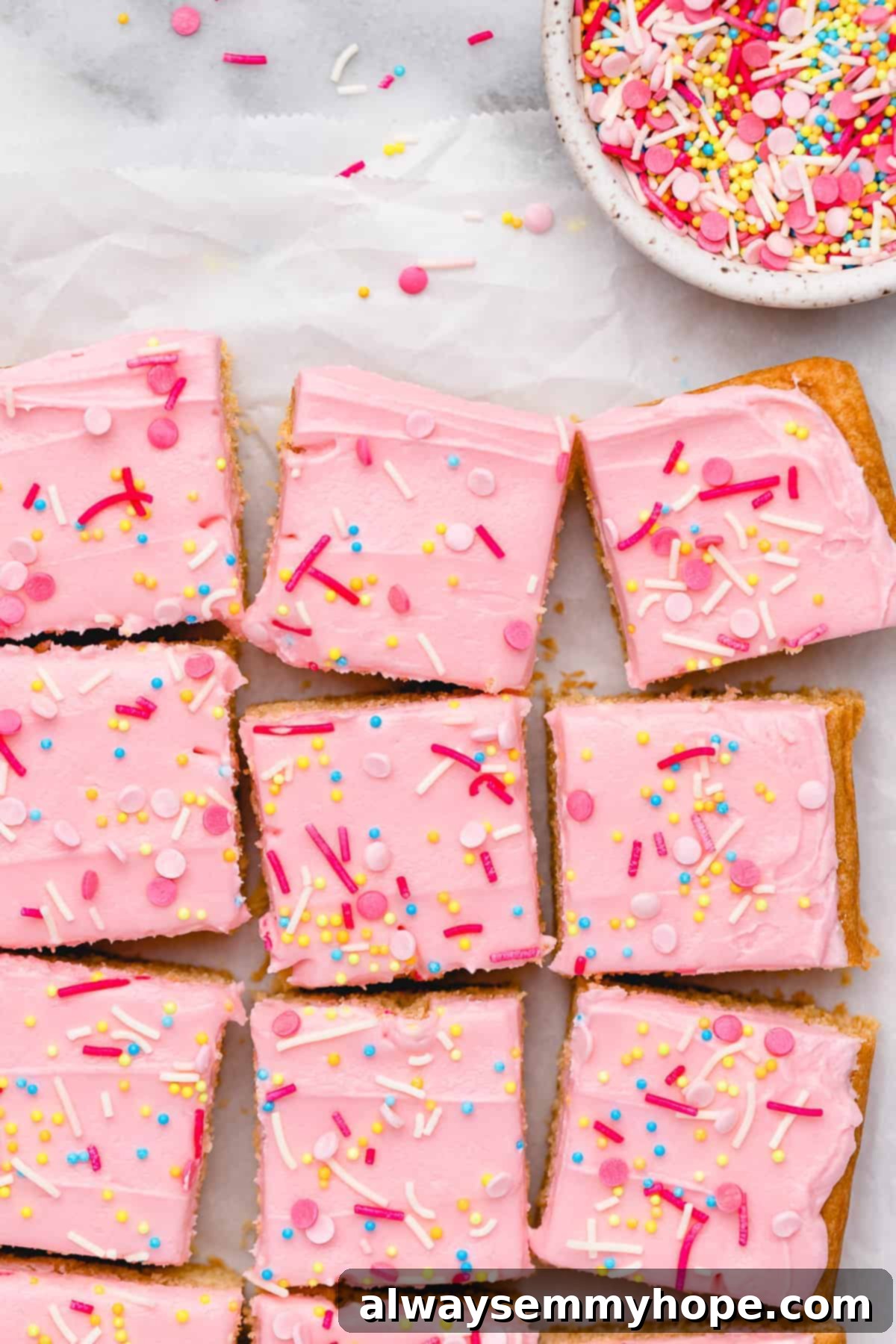 These vegan frosted sugar cookie bars have all the flavor of a classic sugar cookie, without the rolling and cutting, or the dairy and eggs! Overhead view of vegan sugar cookie bars with bowl of sprinkles