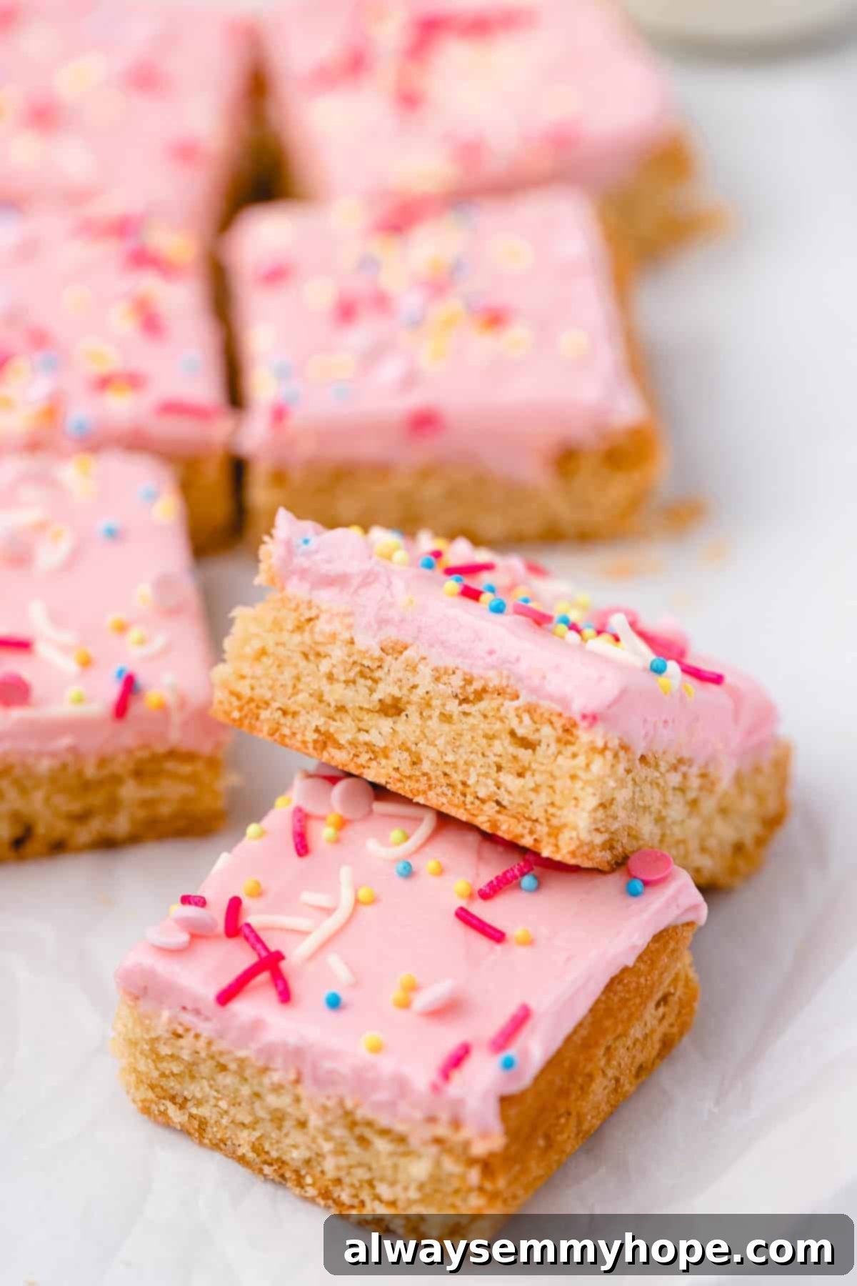 These vegan frosted sugar cookie bars have all the flavor of a classic sugar cookie, without the rolling and cutting, or the dairy and eggs! Sugar cookie bars on parchment paper