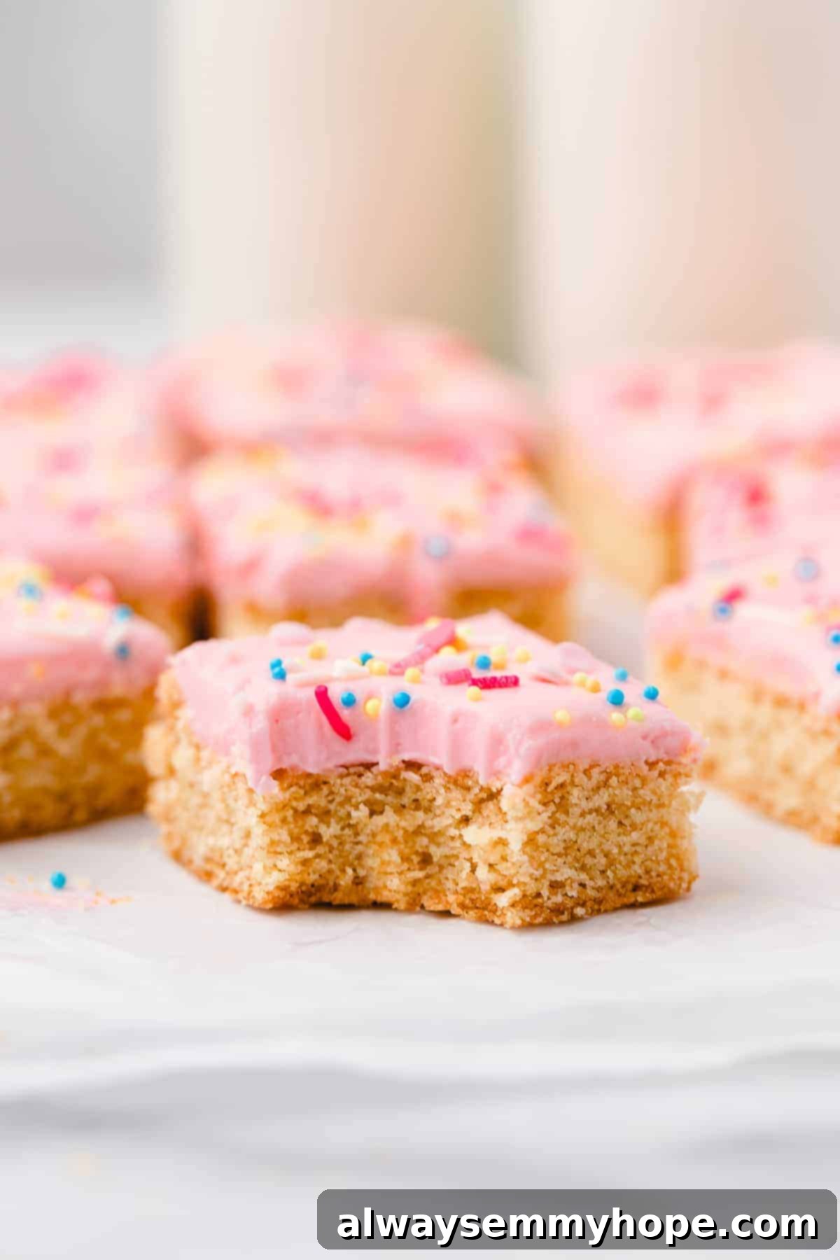 These vegan frosted sugar cookie bars have all the flavor of a classic sugar cookie, without the rolling and cutting, or the dairy and eggs! Vegan sugar cookie bar with bite taken out
