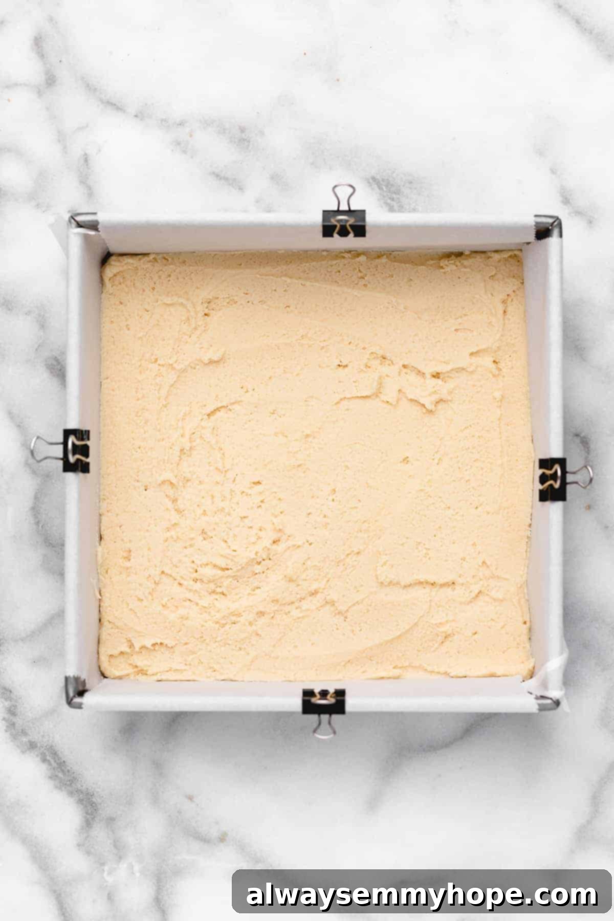 These vegan frosted sugar cookie bars have all the flavor of a classic sugar cookie, without the rolling and cutting, or the dairy and eggs! Overhead view of sugar cookie dough in square baking pan