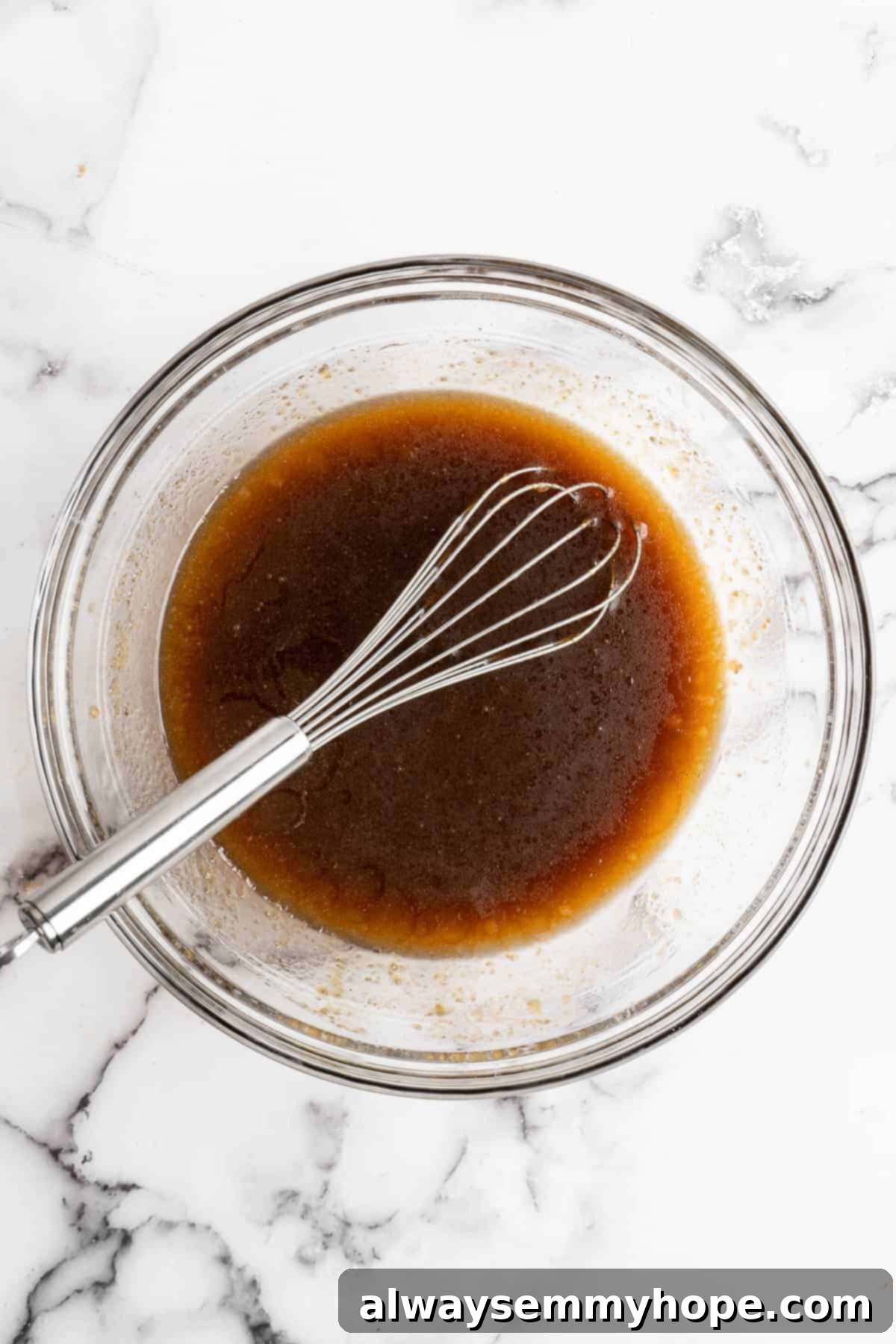 Wet ingredients for carrot cupcakes in glass bowl with metal whisk