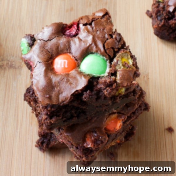 Double Chocolate M&M Brownies are probably one of my favourite brownie recipes! The M&Ms add so much texture and extra chocolate flavour. Overhead shot of Double Chocolate M&M Brownies on a wooden table.