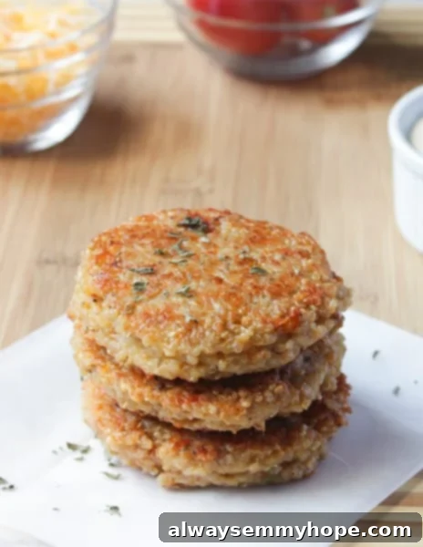 A stack of three vibrant Sun-dried Tomato and Mozzarella Quinoa Veggie Burgers, artfully arranged on a rustic wooden table, garnished with fresh basil leaves. The golden-brown patties showcase visible chunks of sun-dried tomatoes and hints of melted mozzarella.
