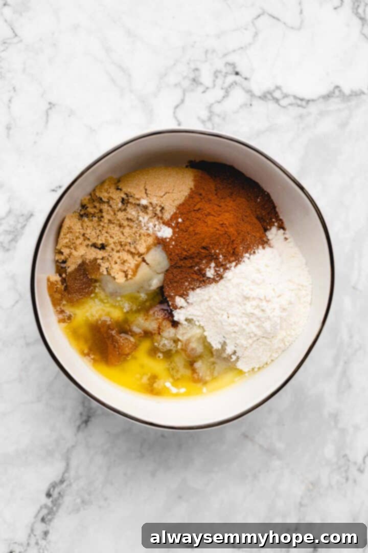Overhead view of brown sugar, melted vegan butter, ground cinnamon, and flour in a bowl for the cinnamon filling.