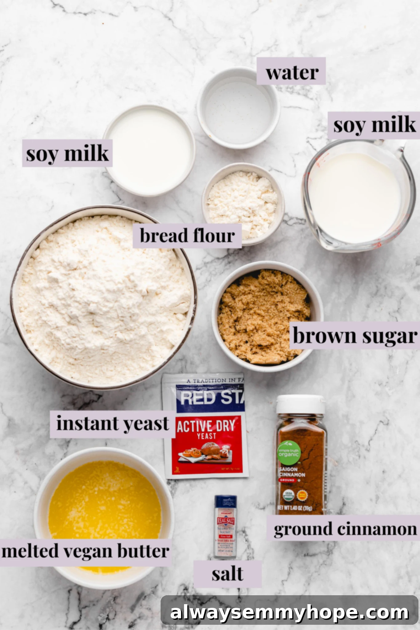 Overhead view of various vegan cinnamon roll ingredients including flour, sugar, milk, and spices on a wooden surface.