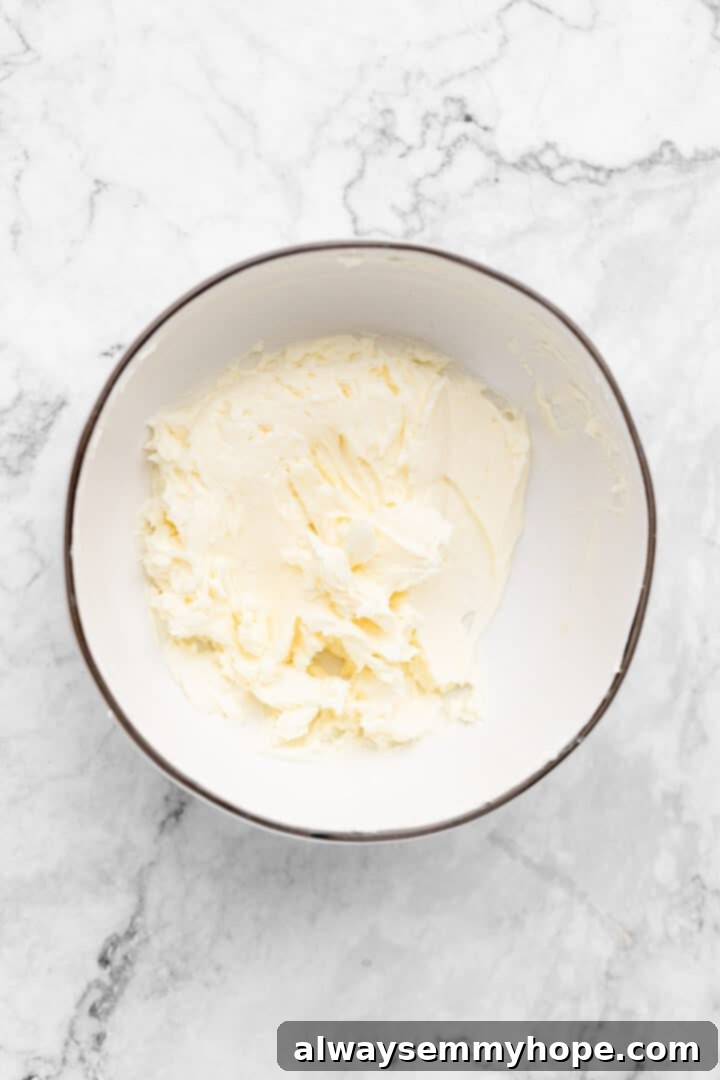 Overhead view of creamed vegan butter and vegan cream cheese in a mixing bowl, light and fluffy.