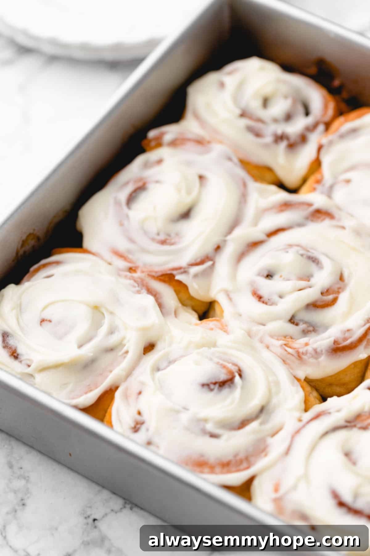 Vegan cinnamon rolls baked to golden perfection, still in a metal baking pan, unfrosted and steaming slightly.