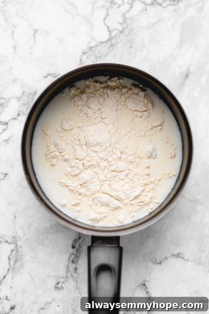 Overhead view of bread flour, soy milk, and water in a small saucepan before whisking.