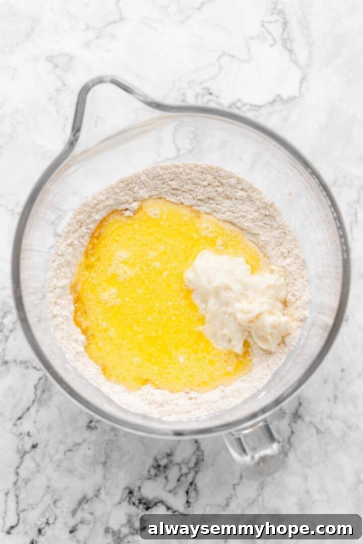Overhead view of wet ingredients being added to the dry ingredients in a mixing bowl for cinnamon roll dough.