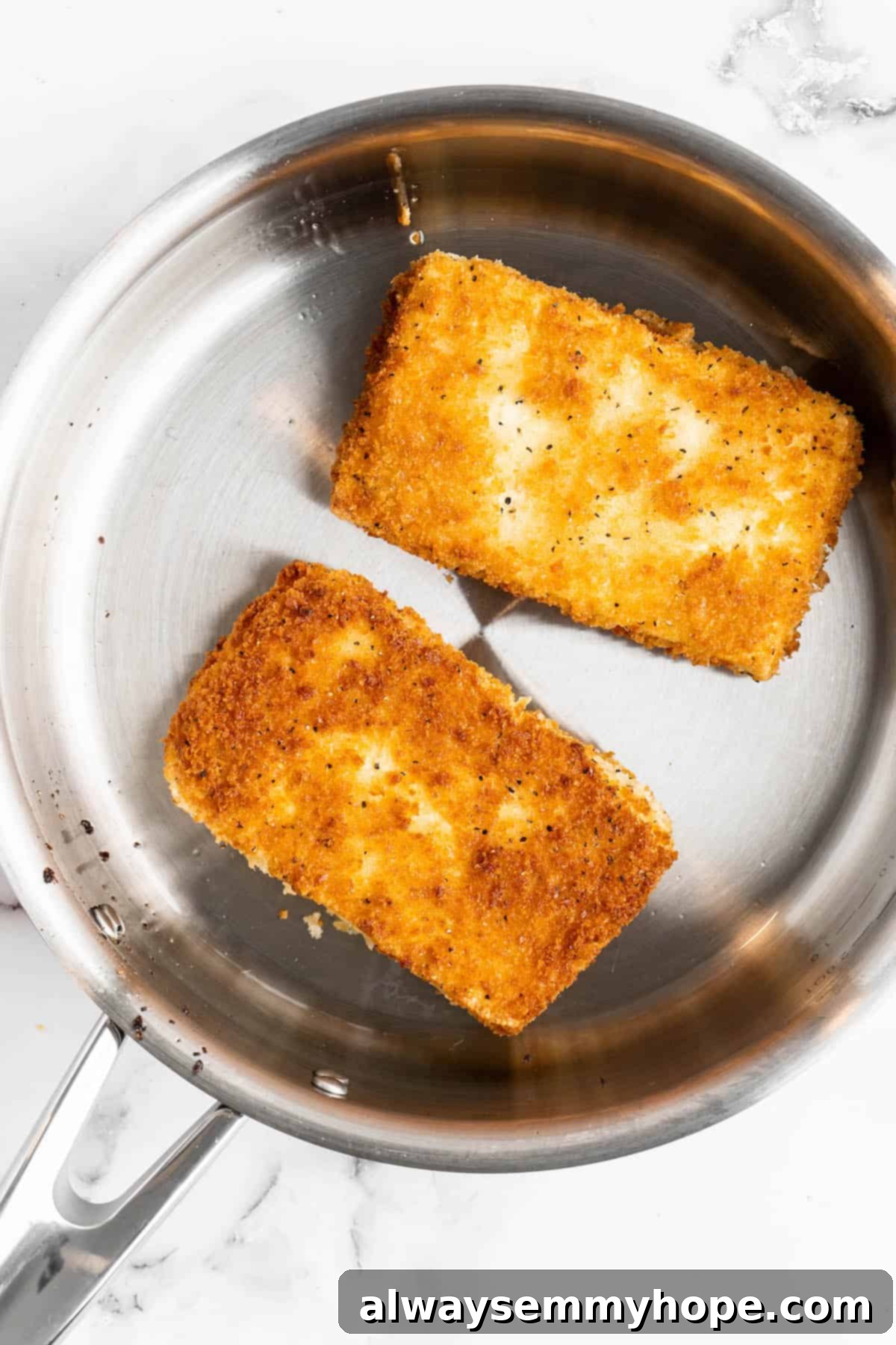 Two tofu katsu cutlets in frying pan