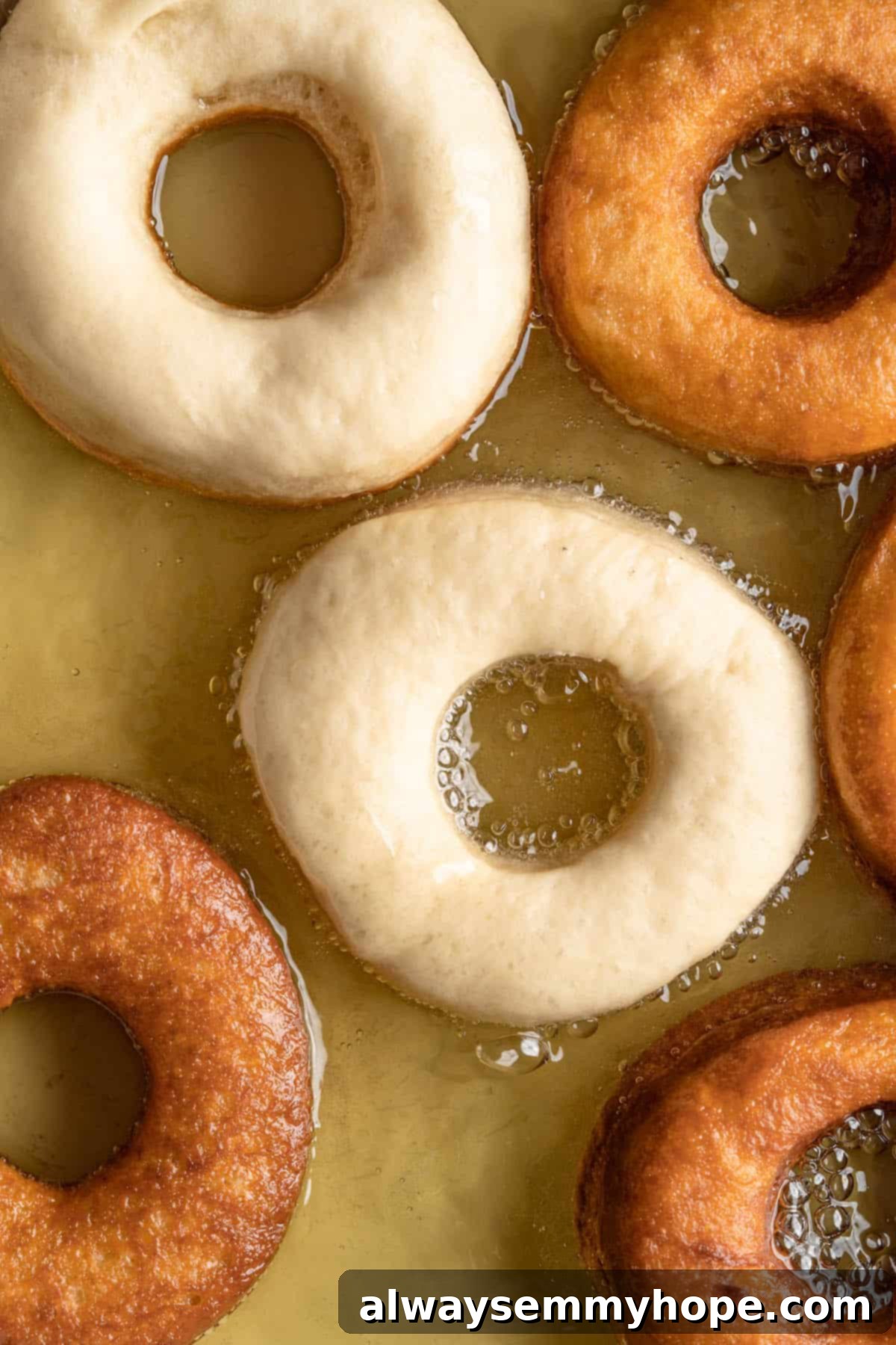 Vegan donuts cooking and browning in hot oil in a skillet