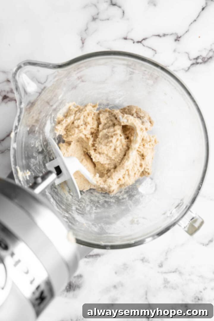 Vegan donut dough being kneaded in a glass stand mixer bowl with a dough hook