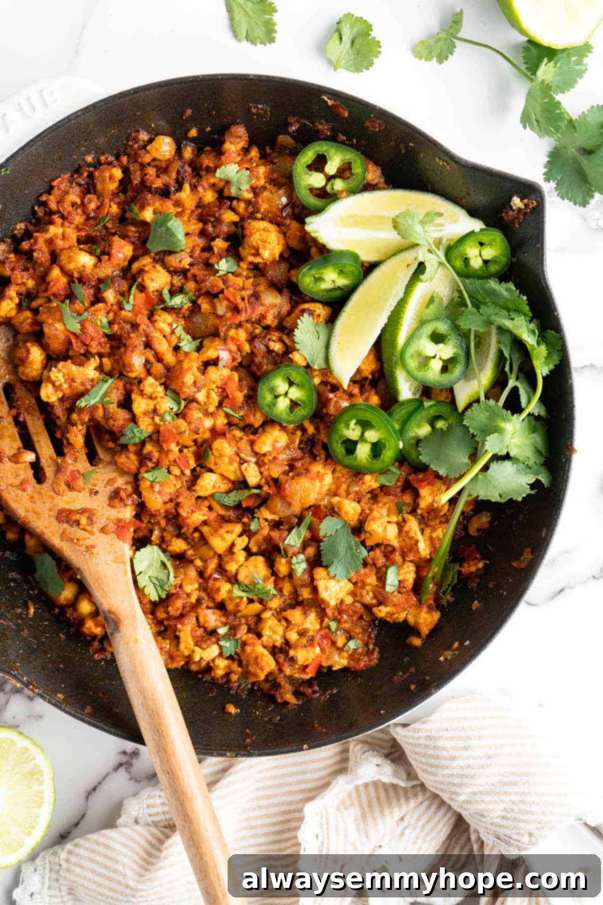 Homemade Chipotle Sofritas 11 Cast iron skillet full of vegan sofritas with a wooden spoon and fresh garnishes like cilantro and lime wedges