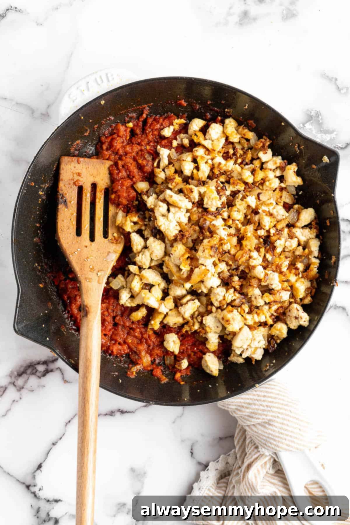 Homemade Chipotle Sofritas 8 Chef stirring crumbled tofu into the simmering sofrito sauce in a skillet