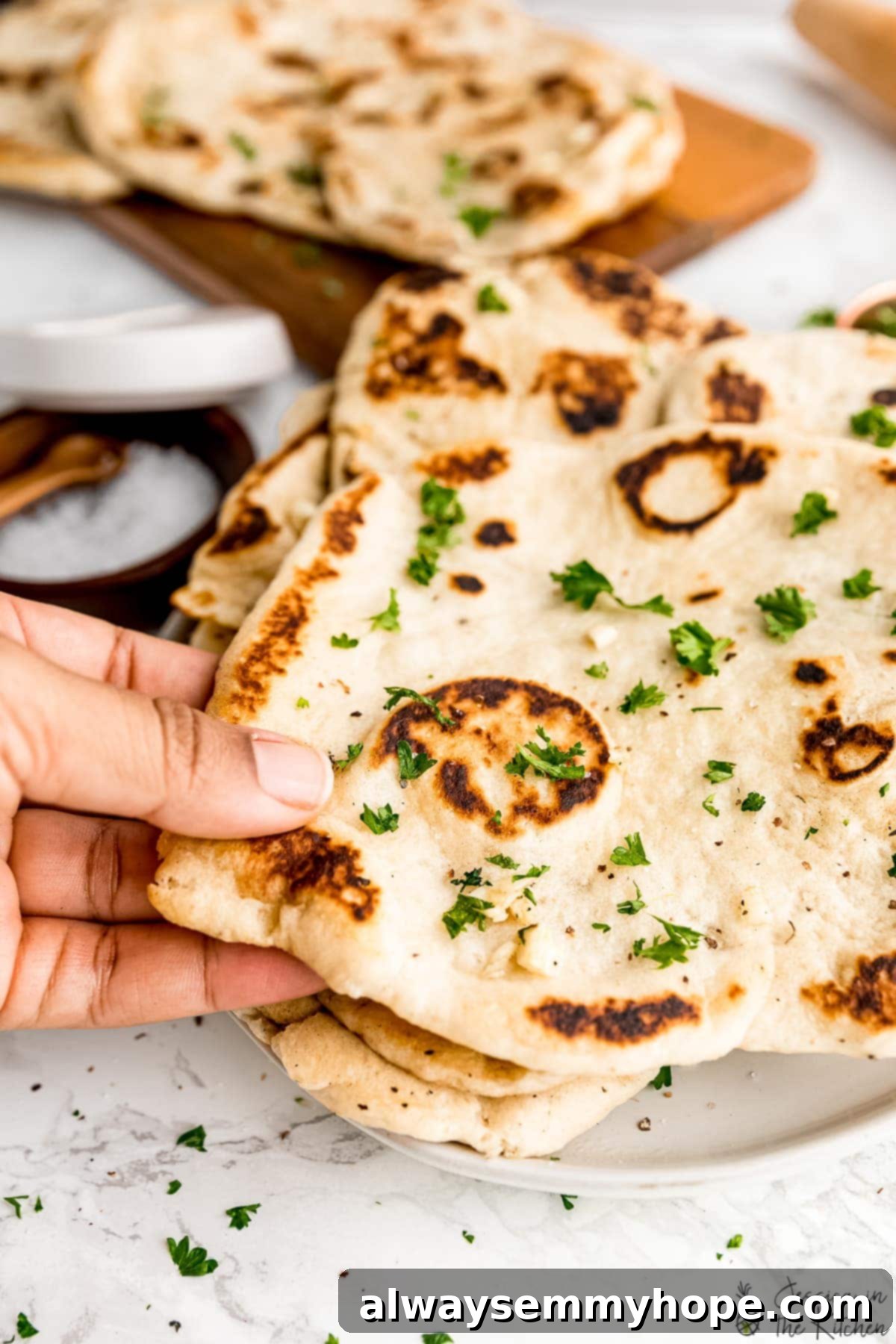 Delicious Homemade Vegan Naan 3 A hand holding a freshly cooked loaf of vegan naan.