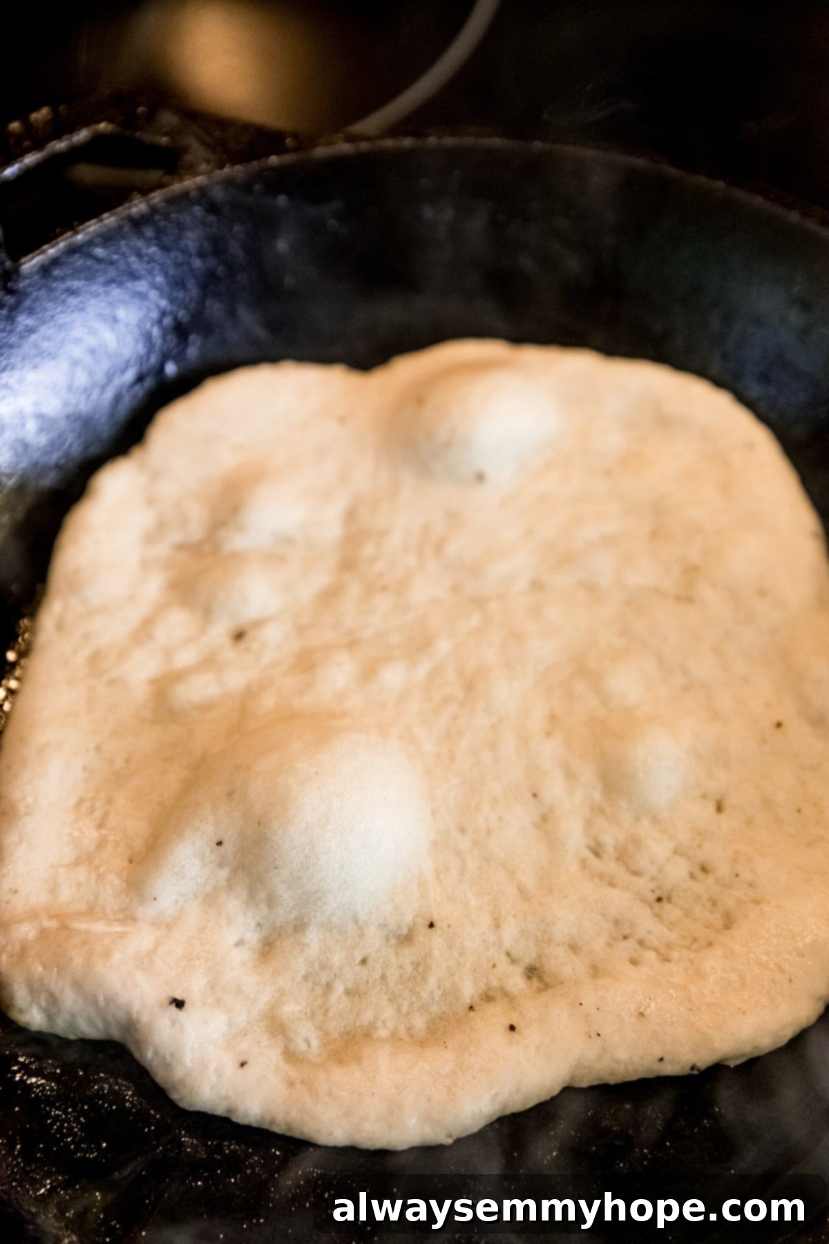 Delicious Homemade Vegan Naan 10 Vegan naan dough cooking in a hot cast iron skillet.