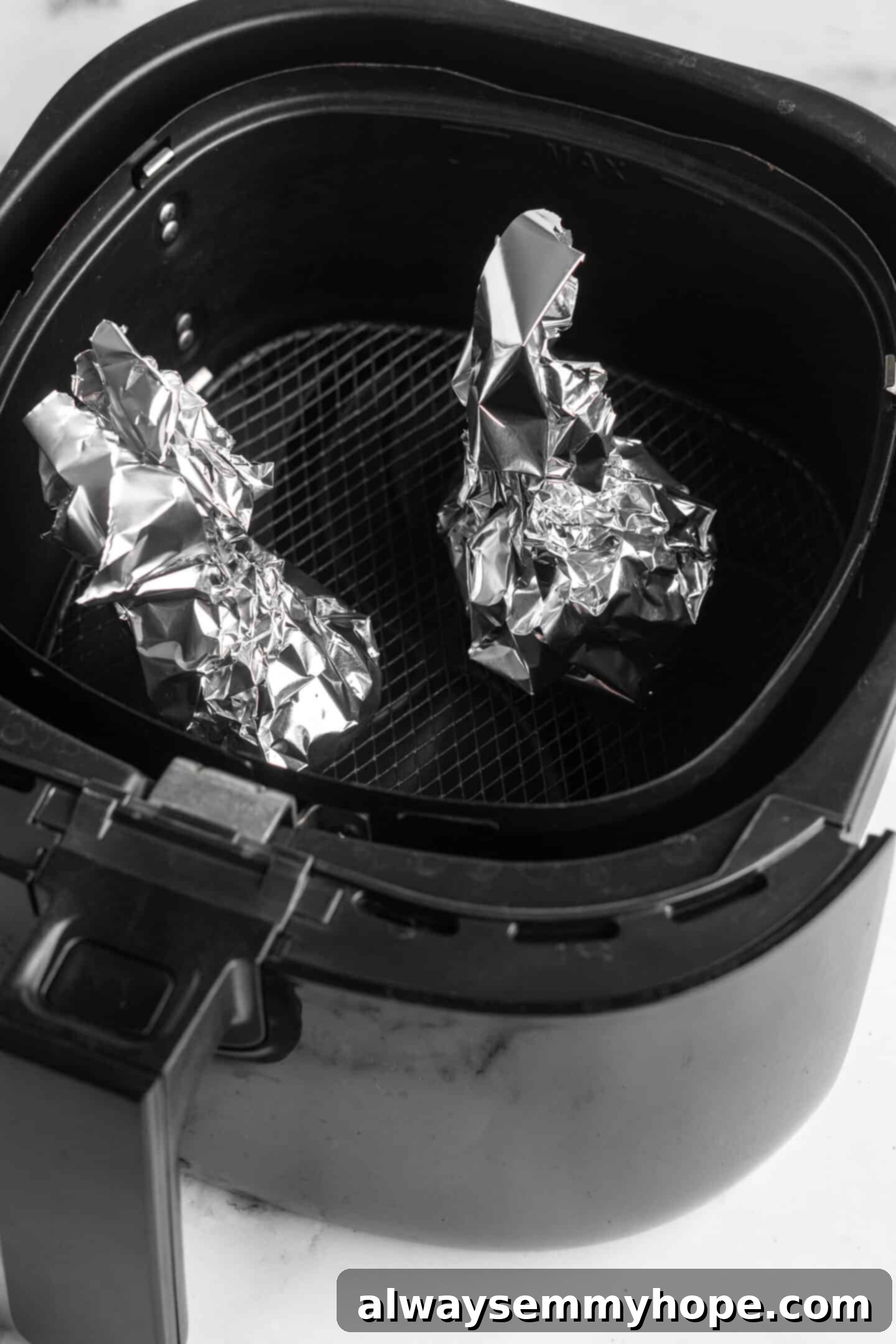 Two garlic heads wrapped in foil in air fryer