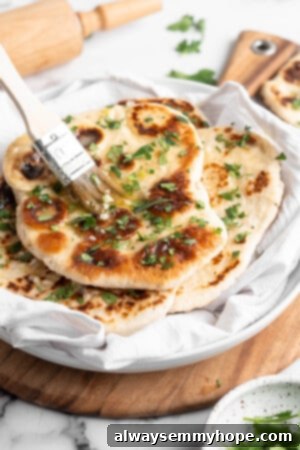 This vegan garlic naan recipe is chewy, soft, and easy to make at home! It's full of garlic flavour and perfect for pairing with curry! Brushing melted garlic butter onto warm naan, adding the finishing touch.