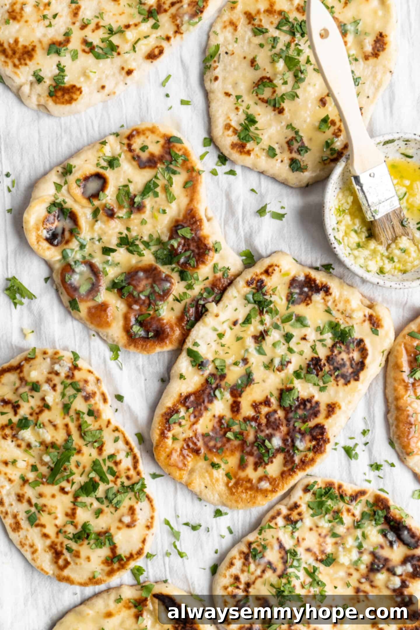 This vegan garlic naan recipe is chewy, soft, and easy to make at home! It's full of garlic flavour and perfect for pairing with curry! Overhead close-up view of freshly cooked vegan garlic naan, showing its soft, bubbly texture.