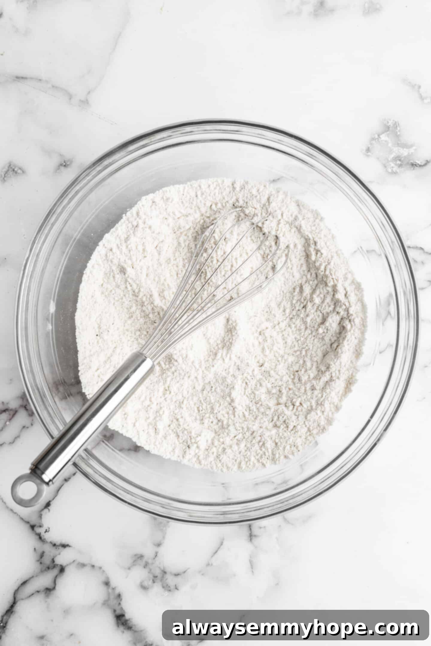 This vegan garlic naan recipe is chewy, soft, and easy to make at home! It's full of garlic flavour and perfect for pairing with curry! Overhead view of dry ingredients for garlic naan in a large glass bowl, perfectly mixed.